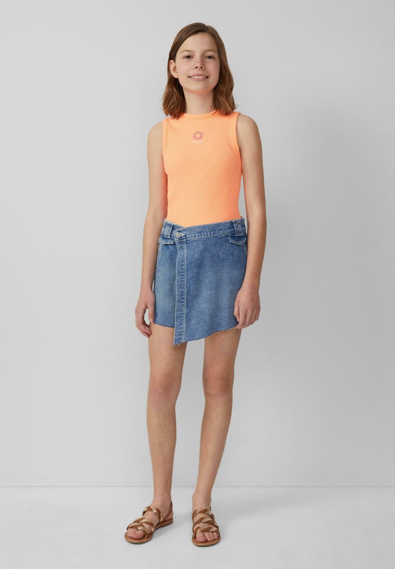Neon oranje mouwloze ribbed top met een zonontwerp, gecombineerd met een blauwe denim wikkelrok en bruine bandjes sandalen.