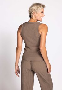 Brown textured tank top with a fitted design, featuring a subtle ribbed pattern and sleeveless cut, paired with matching loose-fit pants.