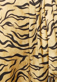 Stof met een beige achtergrond en golvende zwarte tijgerstrepen. Gladde textuur, zachte val en een uitgesproken dierenprintontwerp.