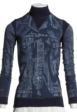 Camiseta de cuello alto azul marino con un estampado realista de chaqueta vaquera, mangas largas y detalles de botones en un torso de maniquí blanco.