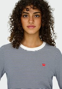 Gestreepte lange mouw shirt met marineblauwe en witte strepen, voorzien van een kleine rode hart borduursel op de borst en een witte ronde hals.