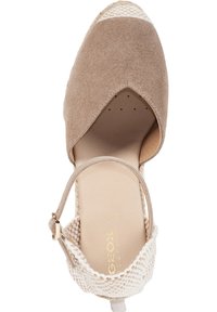 Beige suede espadrille with a woven fabric heel and ankle strap. Features a rounded toe and notable v-shape cutout at the front.