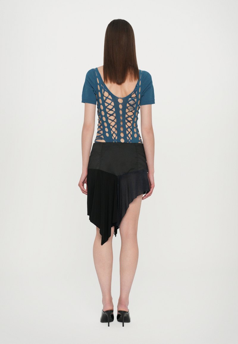 Blue short-sleeve top with a crisscross back design; paired with an asymmetric black skirt showing varying fabric textures. Black heels.