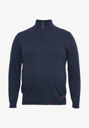 Tumedas sinine kootud aluspluus, mida iseloomustab kõrge krae, tõmblukuga sulgemine ja väike pruun nahklogoga märk ääres.