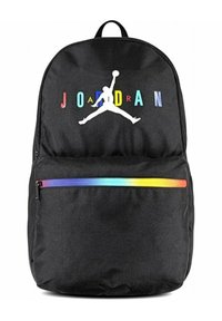 Mochila de tela negra con un gran logo Jumpman blanco y letras "JORDAN" multicolores. Incluye un bolsillo con cremallera horizontal a rayas de colores del arcoíris.
