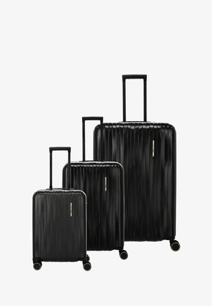 Trois valises rigides noires de tailles petite, moyenne et grande, chacune avec des poignées télescopiques et quatre roues pivotantes.