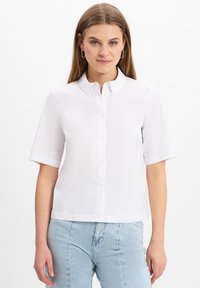Kortarmig wit shirt met een button-down kraag, voorzien van een gladde textuur en een rechte snit, gecombineerd met lichtblauwe jeans.