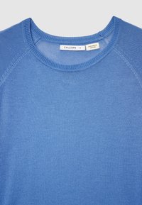 Blauer Baumwollpullover mit Rundhalsausschnitt, geripptem Kragen und Raglanärmeln. Mit einem Etikett mit der Aufschrift "CALLIOPE" und "ZERO WASTE DESIGN."