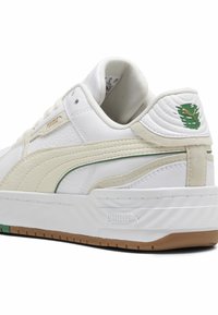 Baskets en cuir blanc à finition texturée, accents crème, logo vert et semelle en caoutchouc gomme. Équipées d'un col rembourré et de bandes latérales.