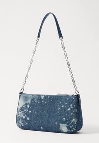 Sac à bandoulière en denim avec un motif éclaboussé bleu clair, une chaîne argentée, une forme rectangulaire, une fermeture zippée et une surface texturée.
