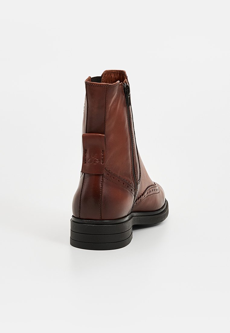 Braune Lederstiefelette mit seitlichem Reißverschluss, detaillierter Naht und rechteckigem Absatz. Schwarze Gummisohle, glatte Textur und dezente Akzente.