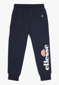 Temno modri trenirke iz bombaža, z elastičnim pasom in zadnjim žepom, z velikim belim logotipom "ellesse" in oranžnim poudarjenjem.