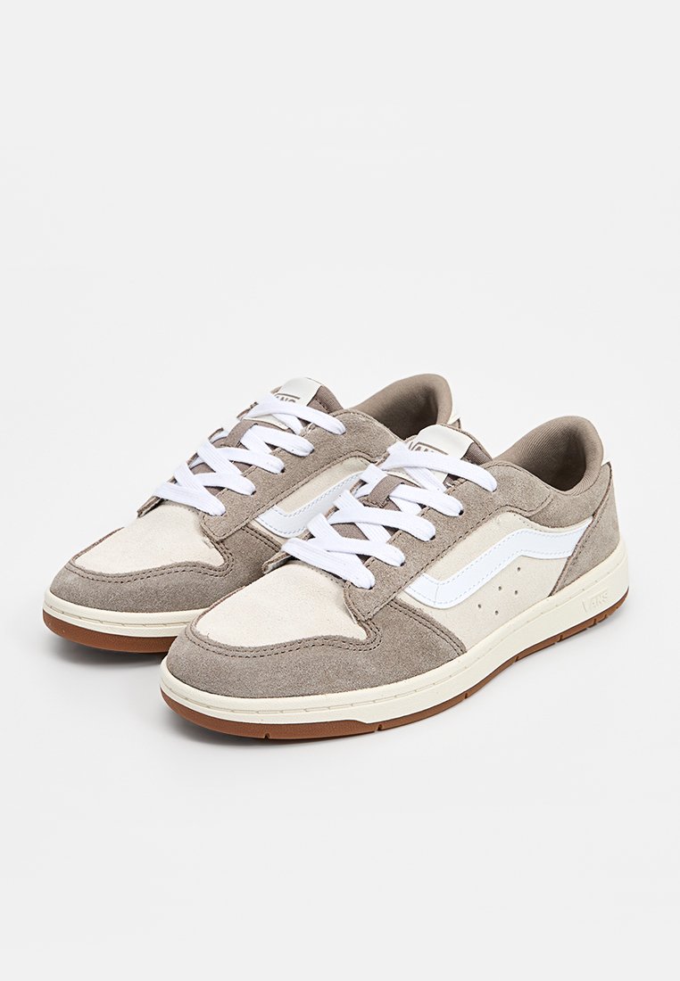 Grau- und cremefarbene Wildledersneaker mit weißen Akzenten und Schnürsenkeln, die mit perforierten Details und einer Gummisohle für besseren Halt ausgestattet sind.