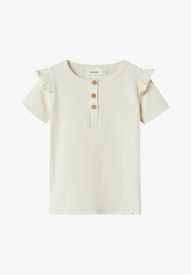 Kremo spalvos, raukšlėtas trumpų rankovių marškinėliai su volanėlėmis ant pečių ir trimis mediniais mygtukais kaklo srityje.