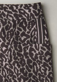 Leopard print fabric with shades of brown and beige, featuring a smooth texture, a waistband with contrasting stripes, and a silver button detail.