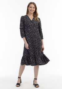 Rochie midi neagră cu imprimeu floral, cu decolteu în V, mâneci trei sferturi și tiv franjurat, având motive florale în nuanțe de violet și alb.