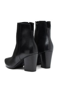 Czarne skórzane botki za kostkę z wysokim blokowym obcasem. Gładka tekstura, zakrzywiony kształt i szczegół z bocznym zamkiem.