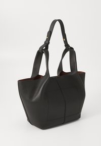 Black leather tote bag with a textured finish, tapered shape, dual handles, and interior in a contrasting brown color. Prominent seam details.
