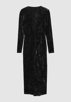 Abito in velluto nero con maniche lunghe, design sopra il ginocchio e taglio dritto. Presenta una leggera lucentezza e una chiusura con zip sul retro.