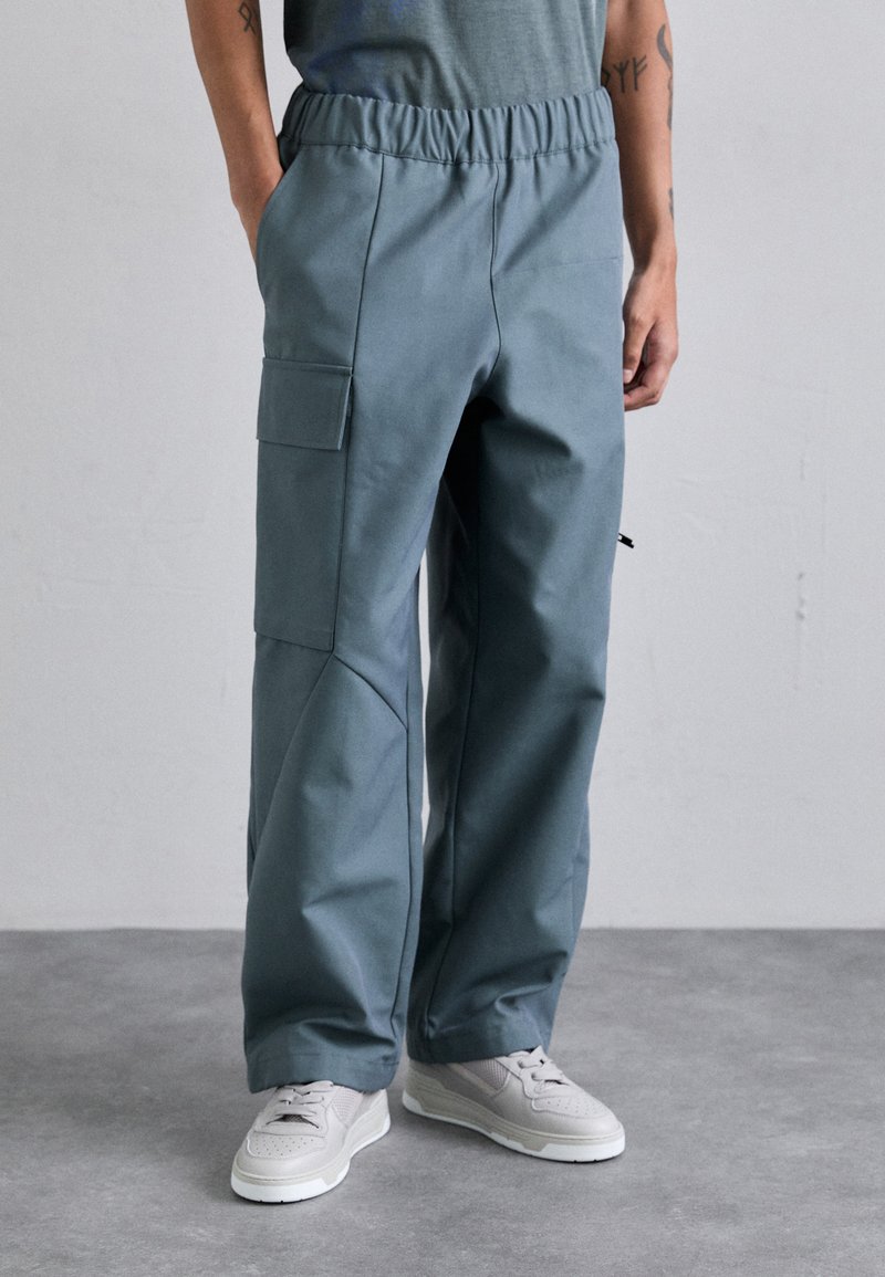 Pantalones cargo de color azul claro con cintura elástica, bolsillos laterales y un diseño ajustado, hechos de un tejido suave y duradero.