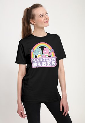 Czarna koszulka z kolorową grafiką dwóch niedźwiedzi, jednego niebieskiego i jednego różowego, trzymających grafiki planet, z napisem "MARTIAN BABES" poniżej.