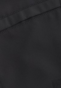 Svart tyg med en jämn textur, med en horisontell söm och en liten präglad logotyp i det nedre högra hörnet.