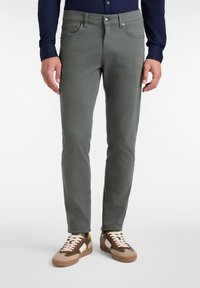 Pantalones de algodón grises con corte slim, cinco bolsillos y costuras en contraste, combinados con zapatillas bajas multicolores.