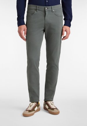 Pantalones de algodón grises con corte slim, cinco bolsillos y costuras en contraste, combinados con zapatillas bajas multicolores.