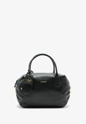 Sac à main en cuir noir avec quincaillerie dorée, de forme arrondie, deux poignées et une étiquette attachée. Présente une finition texturée et de douces plis.