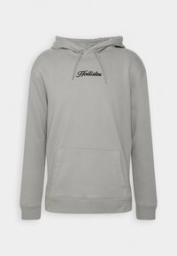 Sudadera con capucha gris claro, con bolsillo frontal y logo negro "Hollister" centrado en el pecho.
