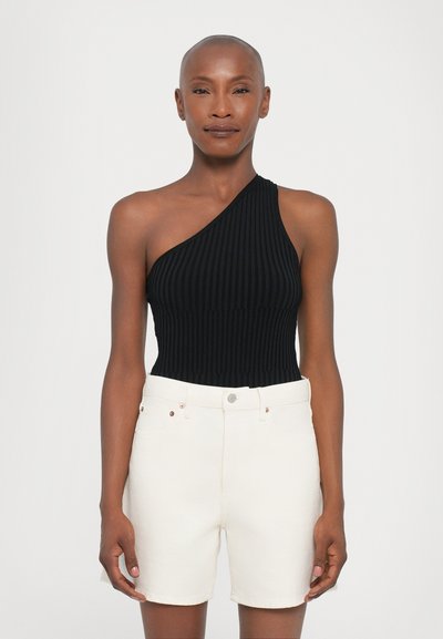 Bodysuit noir à côtes à une épaule associé à un short en jean blanc taille haute. Le bodysuit présente une finition texturée ; le short a une coupe classique.