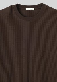 Sweat-shirt en tricot côtelé marron avec un col rond et une texture en relief, étiquette "B2B LOOSE" à l'intérieur du col.