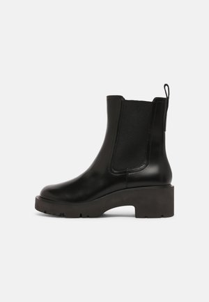 Black leather ankle boots with elastic side panels, rounded toe, and chunky rubber heel for stability. Smooth finish and pull tab at the back.