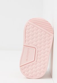 Adidas-sula i mjuk rosa gummi med en texturerad yta som har hexagonala mönster och en logotypdetalj nära fotvalvet.