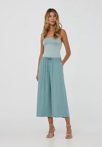 Pantaloni ampi color teal chiaro con vita elasticizzata e lacci, abbinati a un top aderente in teal chiaro. Tessuto morbido e vestibilità rilassata.