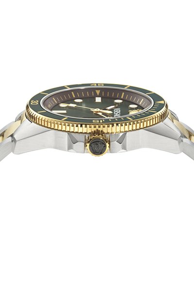 Luxus karóra arany és ezüst fém szíjjal, zöld számlappal, aranyperemmel, amelyen percek vannak jelölve, és Medúza emblémával a koronán.