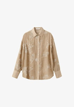 Chemise beige à manches longues boutonnée avec col, ornée d'une broderie florale blanche et de larges poignets.
