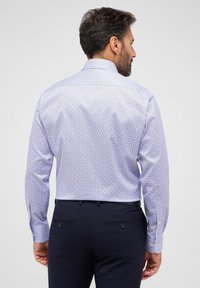 Camicia azzurro chiaro con un motivo floreale, maniche lunghe e collo a bottoni. Realizzata in un tessuto liscio con una vestibilità aderente.