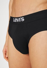 Boxer noir en coton, avec une ceinture douce arborant le logo "Levi's" en blanc. Texture lisse et design ajusté.