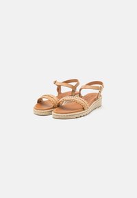 Sandales en cuir tressé de couleur tan avec des brides à la cheville, semelle texturée et talon en jute. Conception à bout ouvert pour plus de respirabilité.