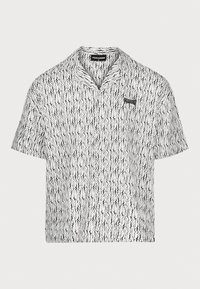 Camisa de manga corta en blanco con un patrón negro en ondas. Presenta un collar con muesca y un pequeño logo negro en el lado izquierdo del pecho.