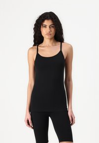 Débardeur noir à fines bretelles, fabriqué à partir d'un tissu lisse et extensible. Il présente un col rond et une coupe ajustée. Idéal pour le superposition.