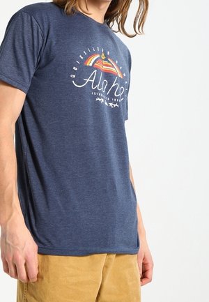 Camiseta de algodón azul marino con un diseño gráfico que incluye un arcoíris y el texto "Aloha" en blanco. Mangas cortas, escote redondo, corte relajado.