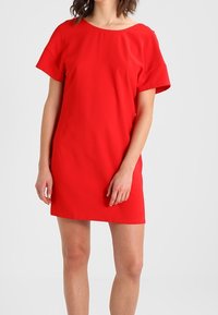 Červené šaty s krátkým rukávem a širokým výstřihem. Mají rovný střih a hladkou texturu, vyrobené z lehkého materiálu.