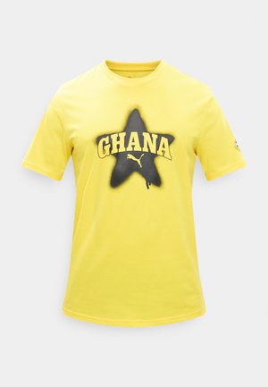 Žluté tričko s krátkým rukávem s černou hvězdou, žlutým nápisem "GHANA" přes hvězdu a malým logem Puma pod nápisem.