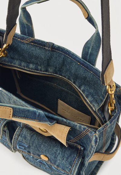 Τσάντα χιαστή από τζιν με στοιχεία από σουέντ, χρυσό φερμουάρ, εμπρόσθια τσέπη με κουμπί και διπλές λαβές, εμφανιζόμενη ανοιχτή για να δείξει το εσωτερικό.