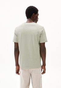 Lichtgroene katoenen t-shirt met korte mouwen en een ronde hals, met een gladde textuur en een eenvoudig ontwerp, van achteren bekeken.