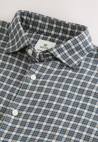 Kariertes Hemd in Schattierungen von Blau, Braun und Creme; verfügt über einen Button-Down-Kragen, weiße Knöpfe und einen weichen, strukturierten Stoff.