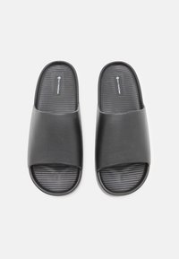 Sorte sandaler med glatt overdel og teksturert, rillelagt såle. Åpen tå-design og minimalistisk stil. Sålen har en flat struktur.