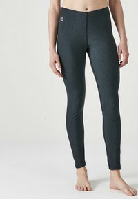 Leggings aderenti color grigio scuro realizzati in tessuto elastico, caratterizzati da una texture liscia e un piccolo logo in vita. Senza cuciture o motivi visibili.